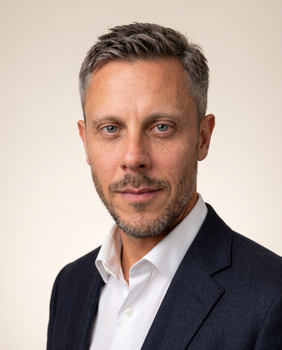 Michał Matuszczyk, portret w naturalnym świetle na tle ściany w kolorze kremowym